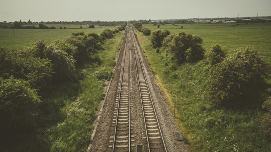overhead shot of train tracks and green pasture