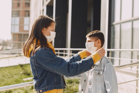mother checking mask on child outside