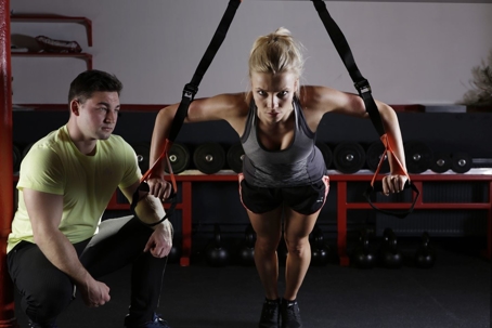coach with a person at the gym using exercise equipment