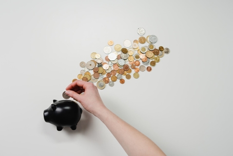 person adding change to a piggy bank